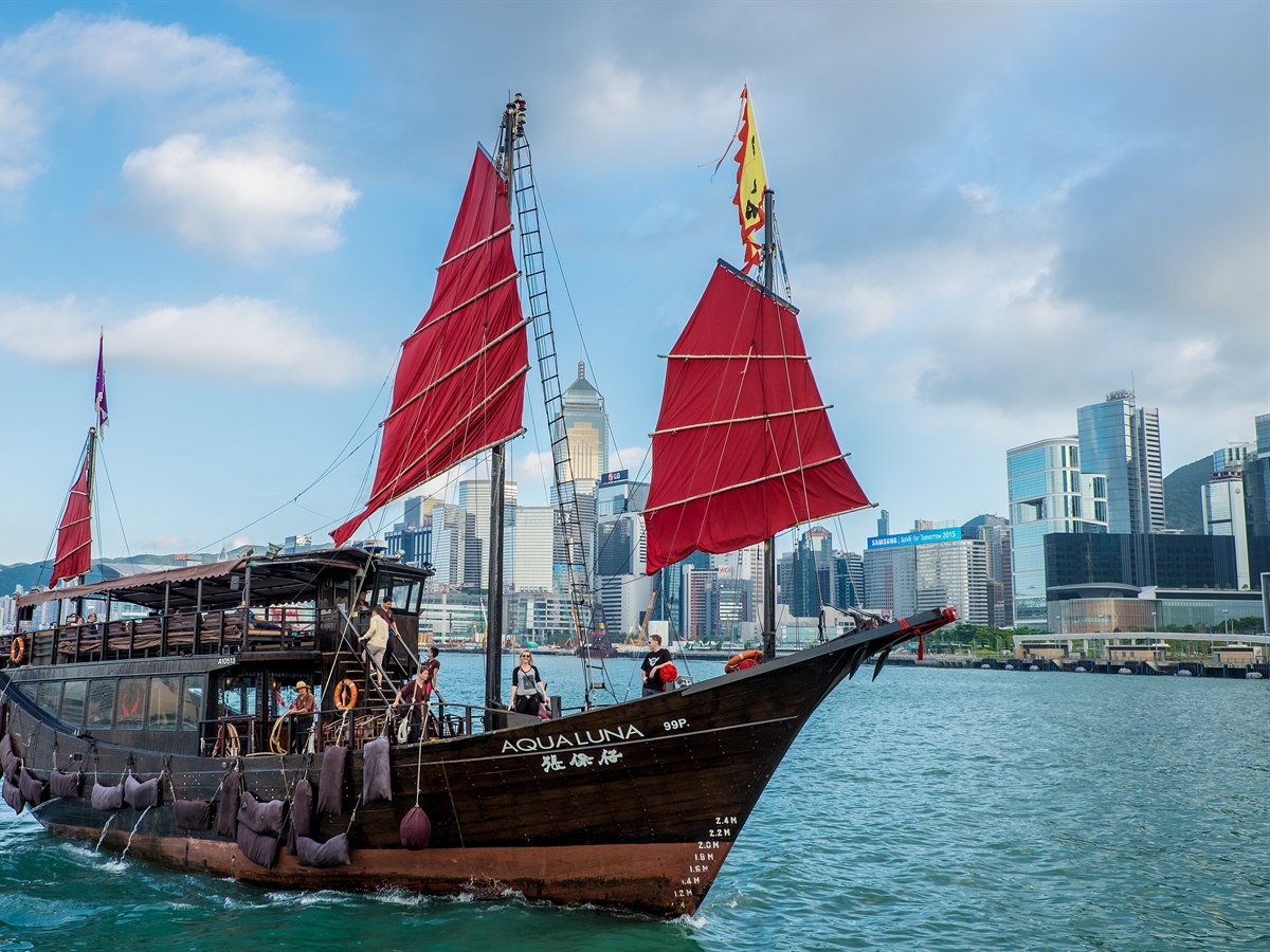Red-sailed junk boat on Victoria Harbour with the Hong Kong skyline