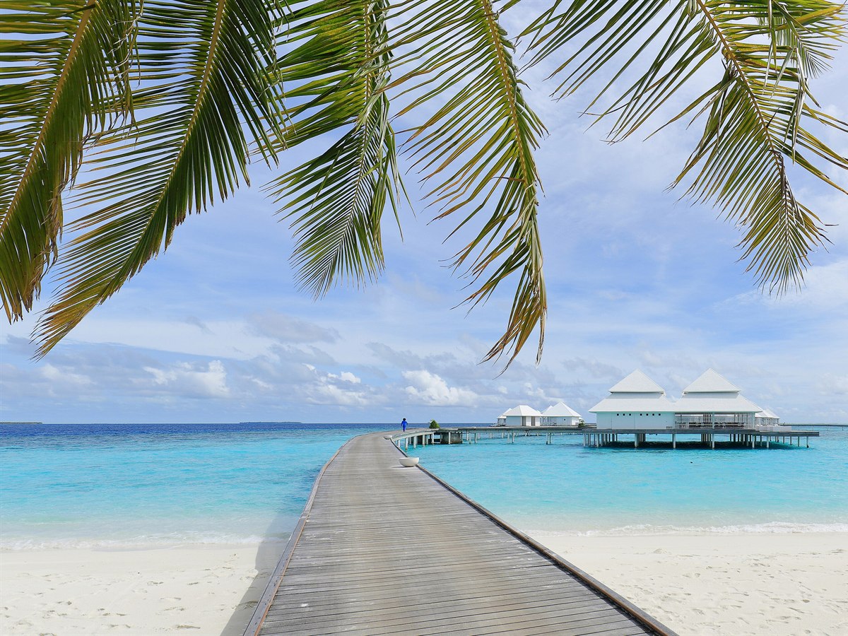 Wooden jetty leading to overwater villas on a turquoise lagoon, Maldives
