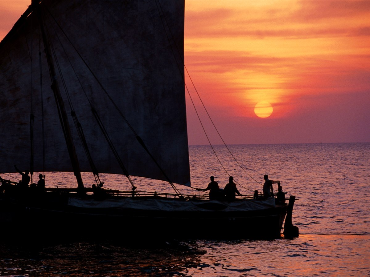 A traditional dhow silhouetted against a red sunset, Zanzibar, Tanzania