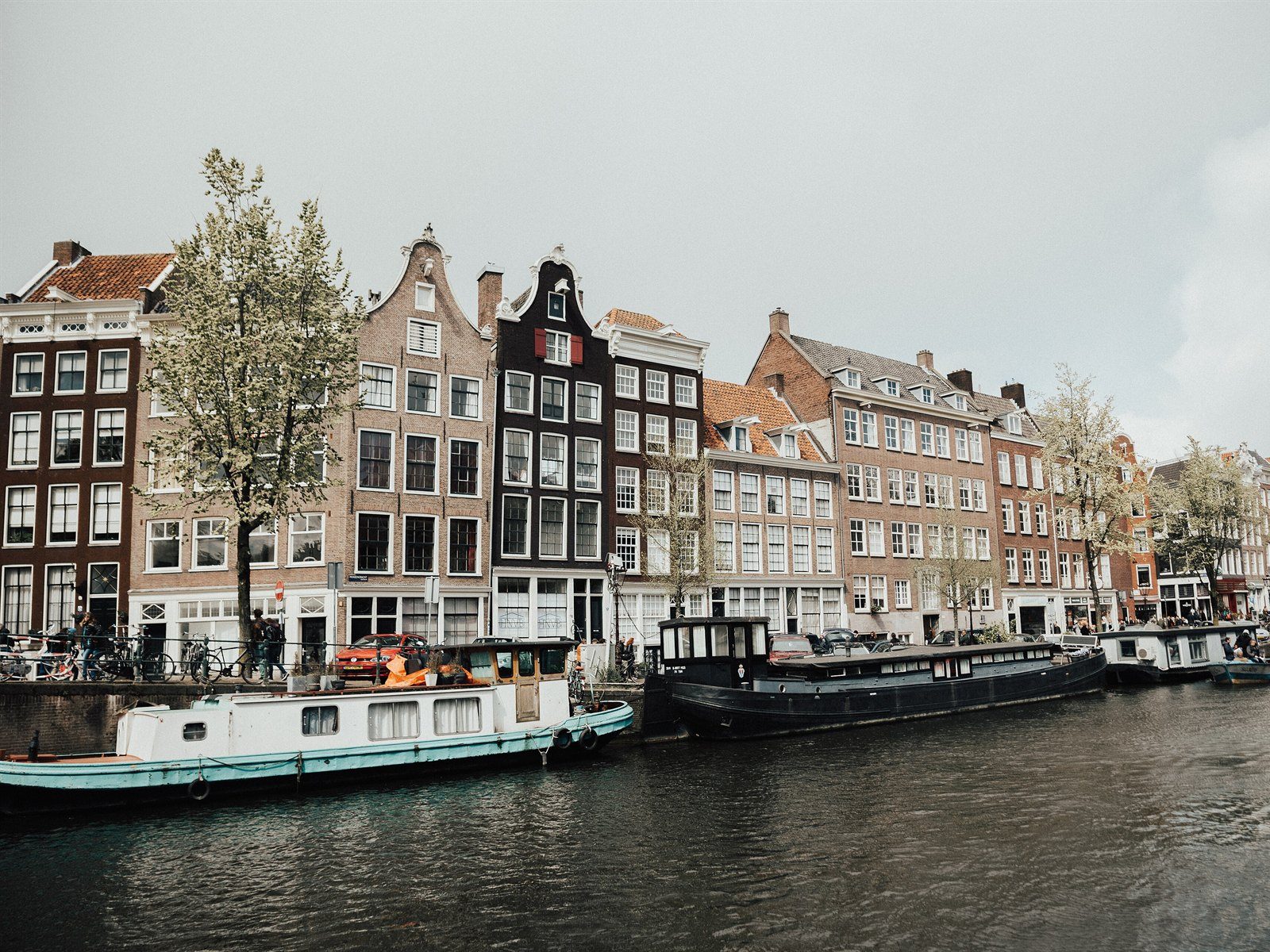 Amsterdam canal lined with tall gabled houses, houseboats and small boats, Jordaan district