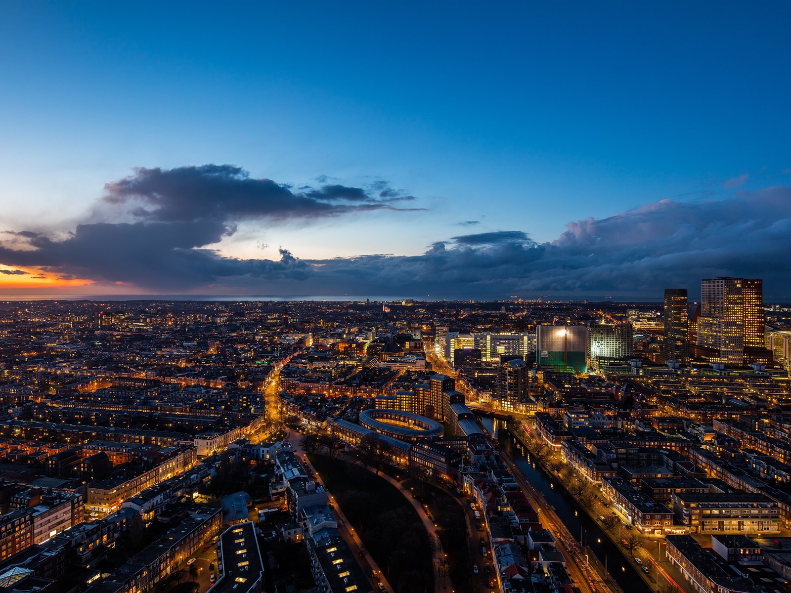 Aerial view of The Hague's skyline at dusk with the North Sea on the horizon