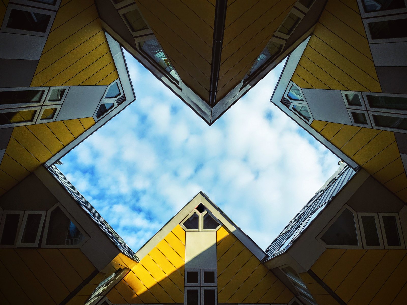 Looking straight up through the gap between Rotterdam's yellow Cube Houses to the sky