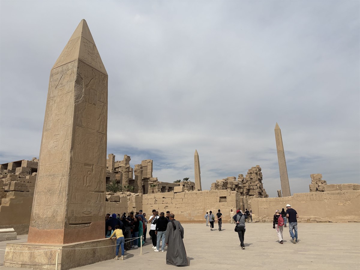 Carved granite obelisk in the Karnak temple complex, with more obelisks and ruined pylons behind, Luxor, Egypt