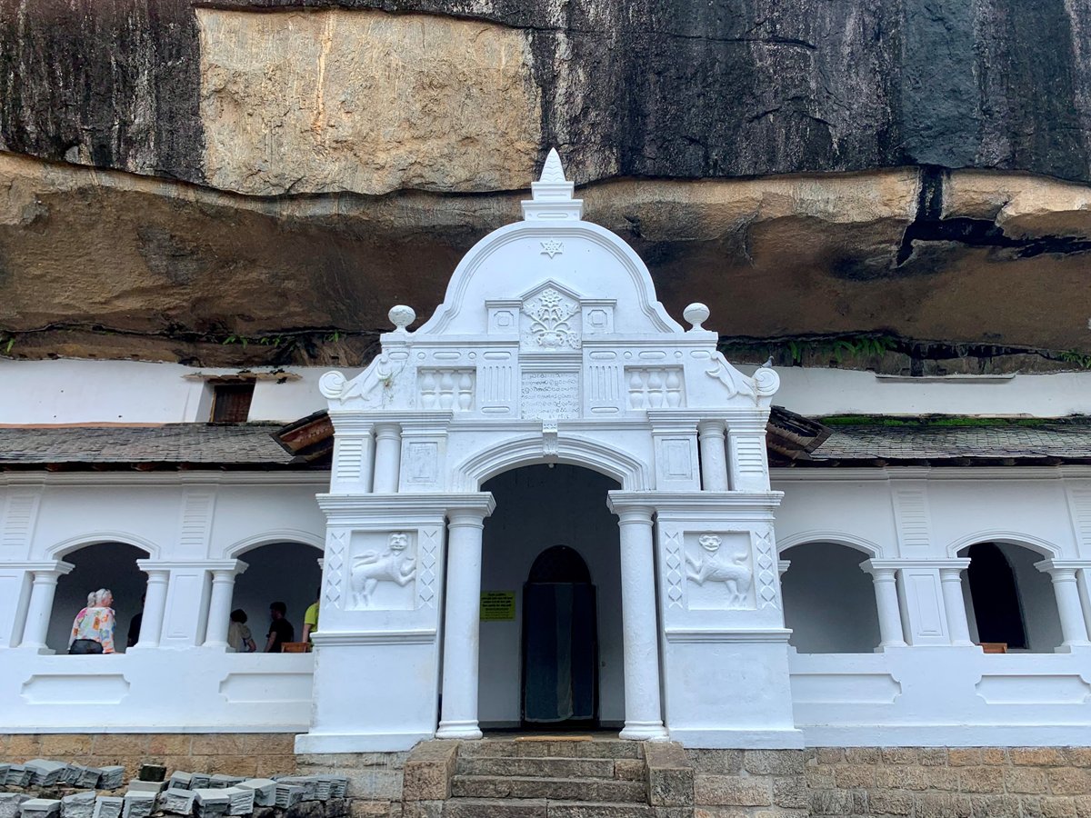 White entrance of the Dambulla cave temple beneath its rock overhang, Sri Lanka