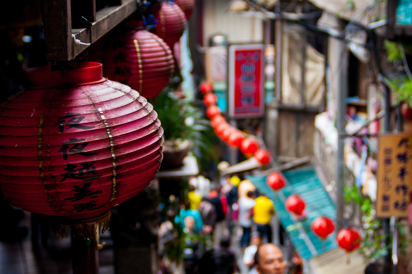 Red paper lanterns hanging over the narrow, busy lane of Jiufen Old Street, Taiwan