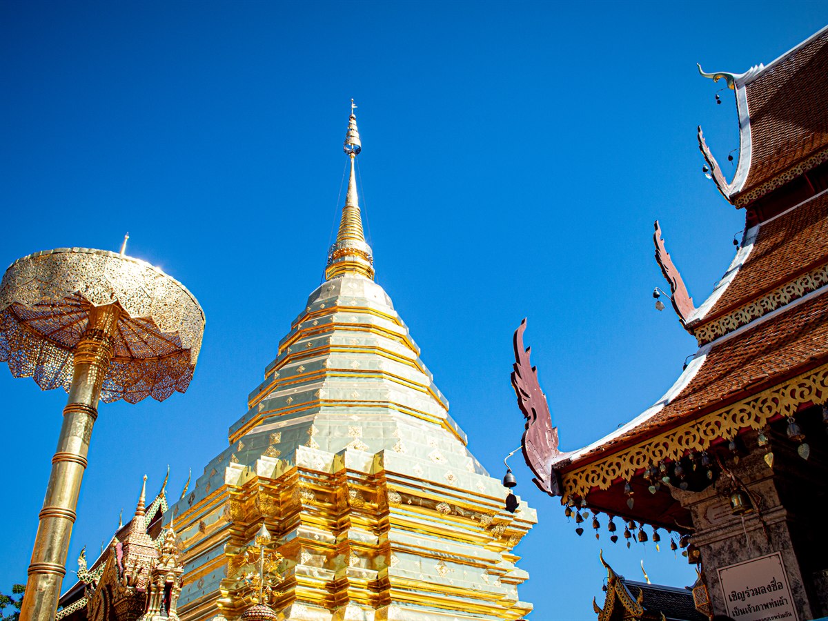The golden chedi of Wat Phra That Doi Suthep against a clear blue sky above Chiang Mai, Thailand