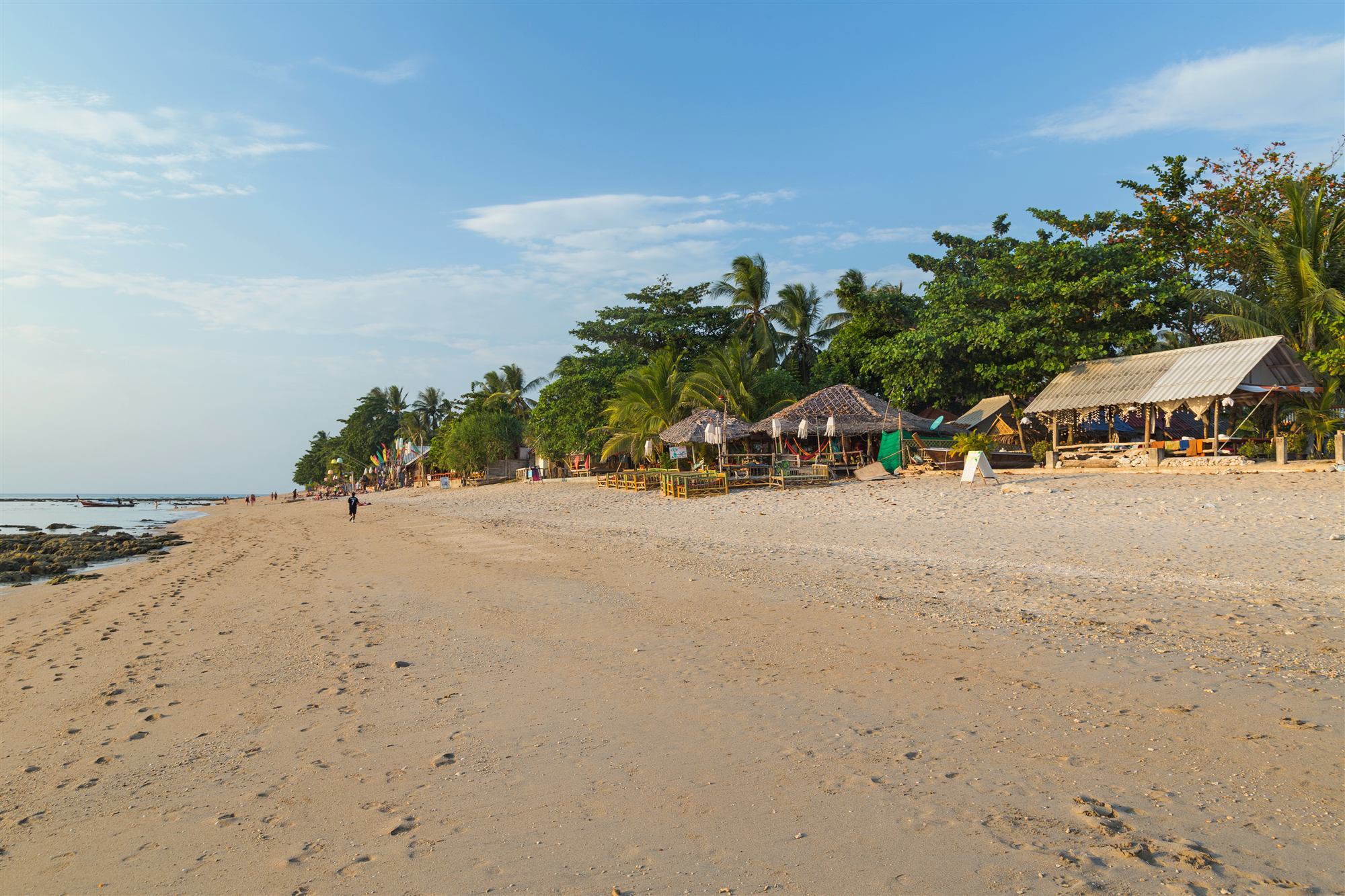A quiet sandy beach lined with palms at sunset on Koh Lanta, Thailand