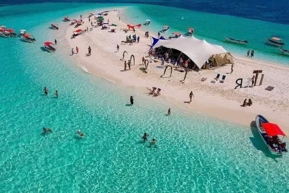 Aerial view of a white sandbank ringed by turquoise shallows and small boats, Zanzibar