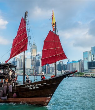 Red-sailed junk boat on Victoria Harbour with the Hong Kong skyline