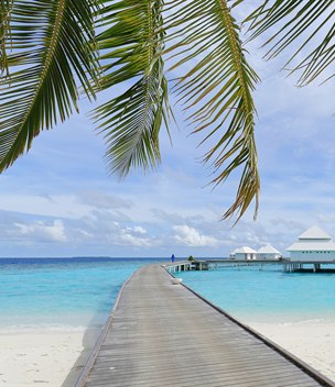 Wooden jetty leading to overwater villas on a turquoise lagoon, Maldives