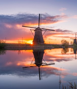 Traditional windmill reflected in a canal at sunrise, Kinderdijk, Netherlands