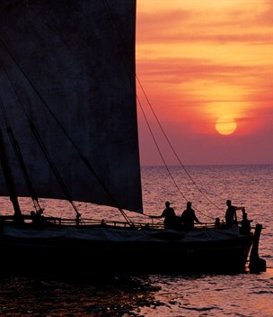 A traditional dhow silhouetted against a red sunset, Zanzibar, Tanzania