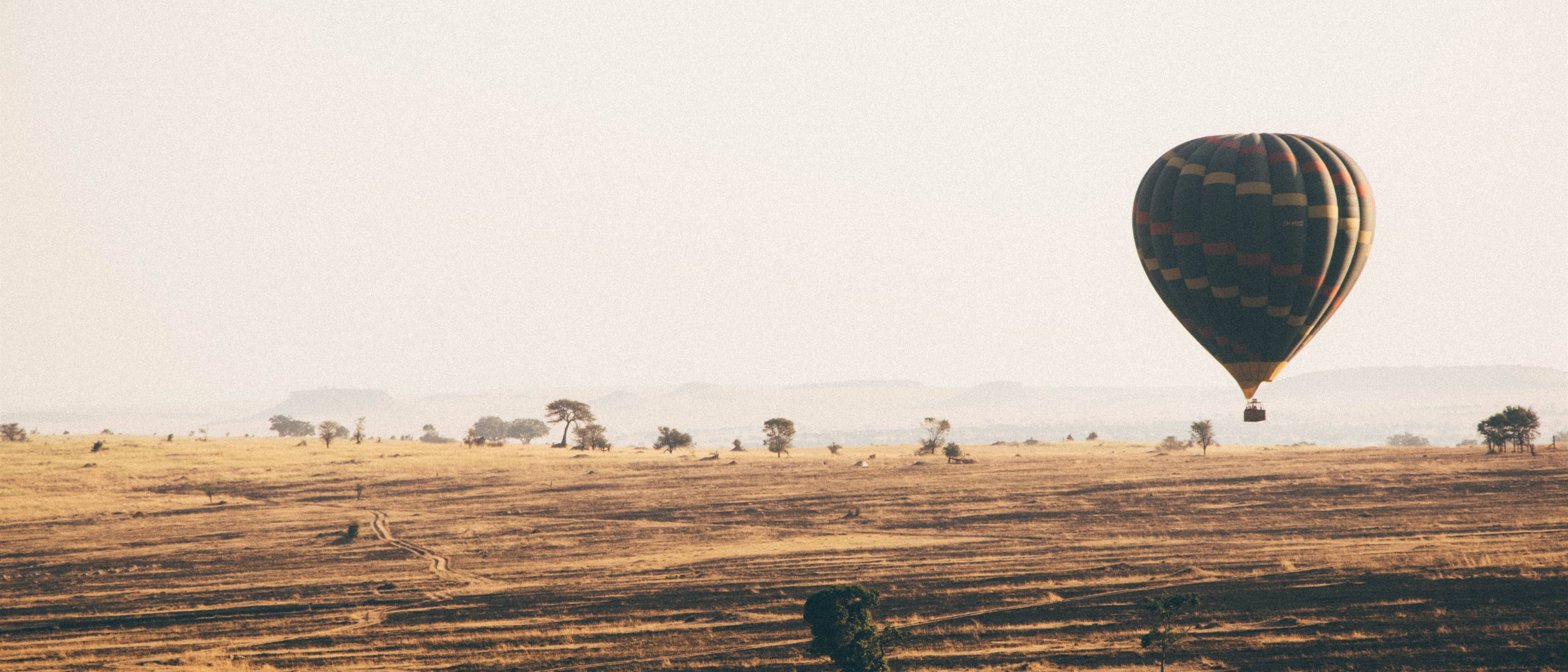A hot-air balloon drifting over the golden Serengeti plains at dawn, Tanzania